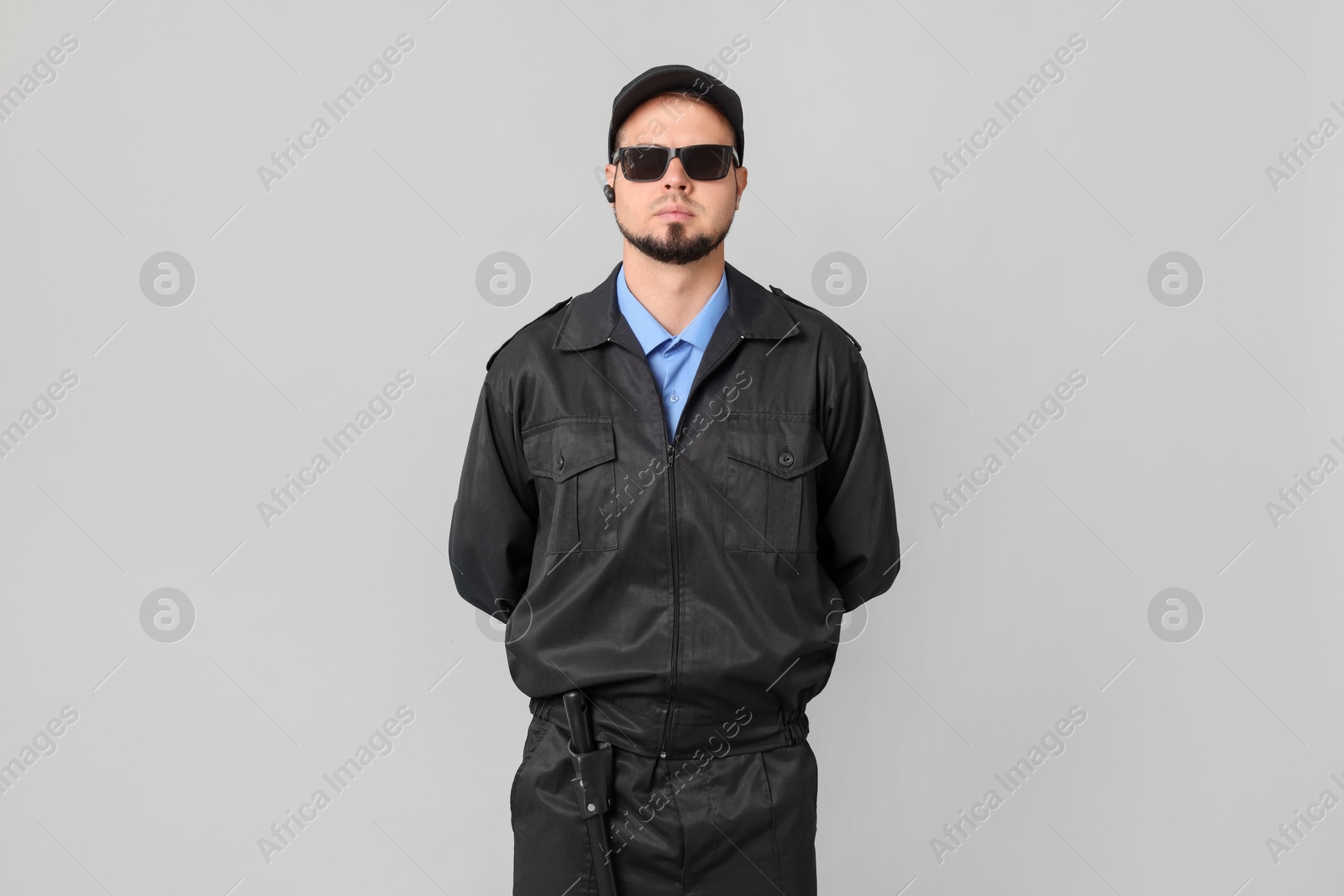 Photo of Security guard in uniform and sunglasses on grey background