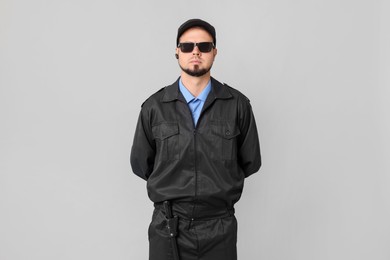 Photo of Security guard in uniform and sunglasses on grey background