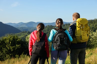 Friends with backpacks in beautiful mountains, back view