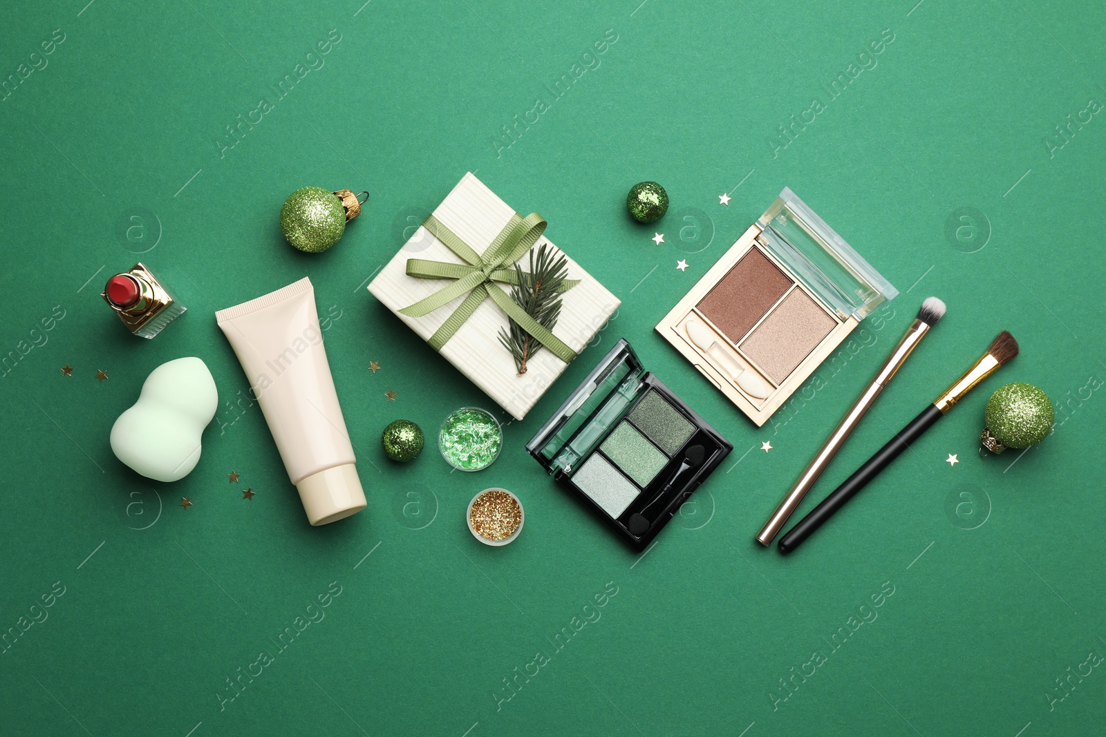 Photo of Flat lay composition with makeup products and Christmas decor on green background