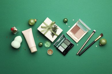 Flat lay composition with makeup products and Christmas decor on green background