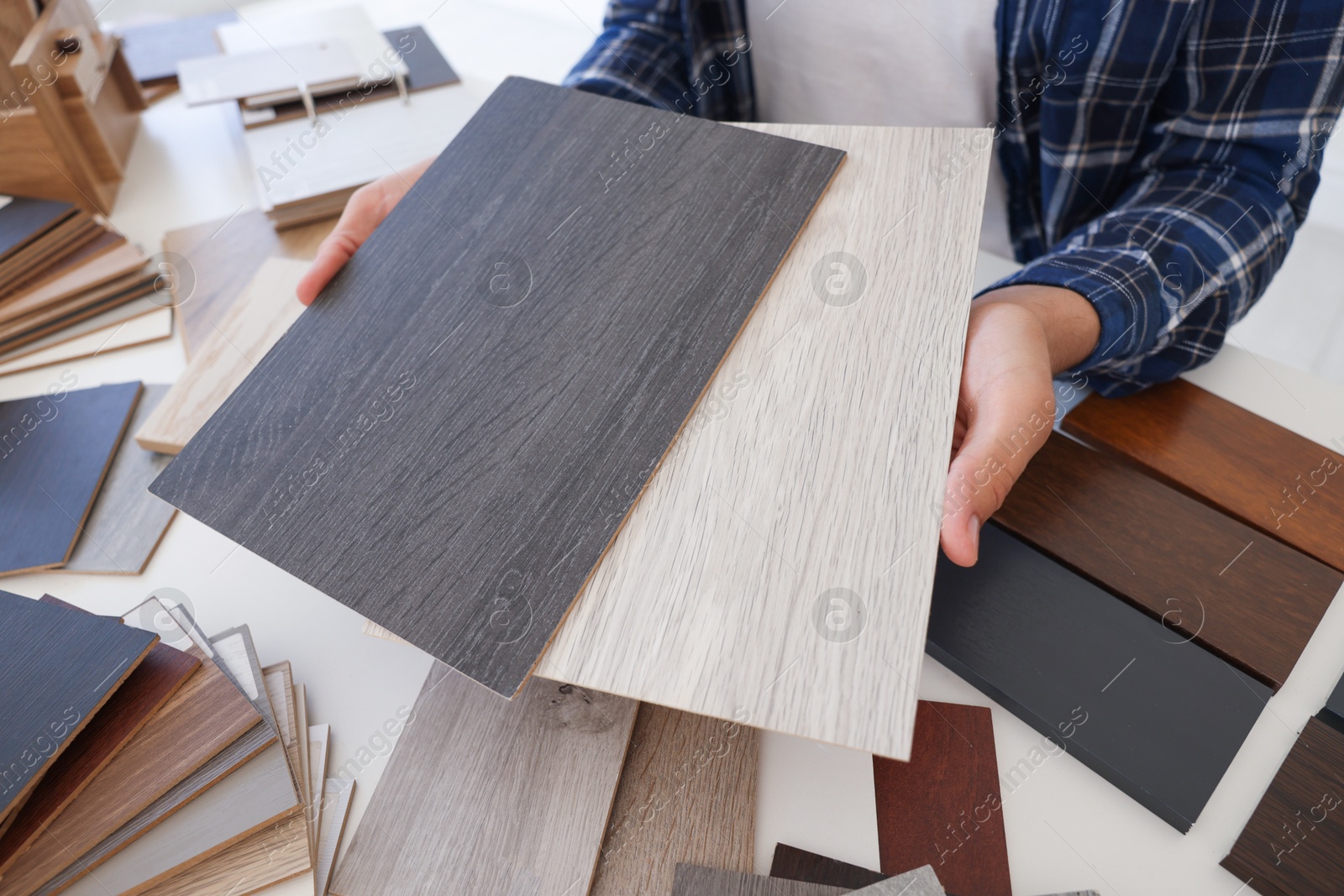 Photo of Man choosing wooden flooring among different samples at table, closeup