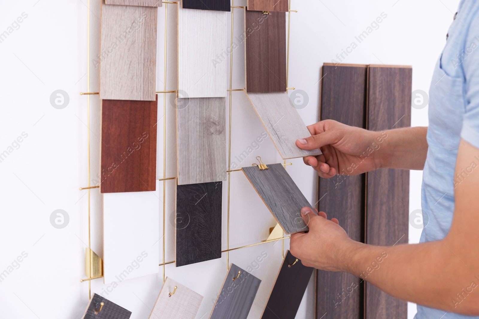 Photo of Man with different samples of wooden flooring indoors, closeup