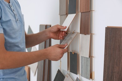 Photo of Man with different samples of wooden flooring indoors, closeup