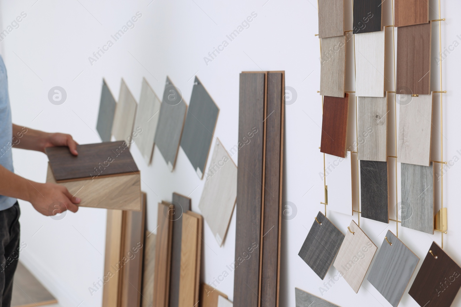 Photo of Man with different samples of wooden flooring indoors, closeup