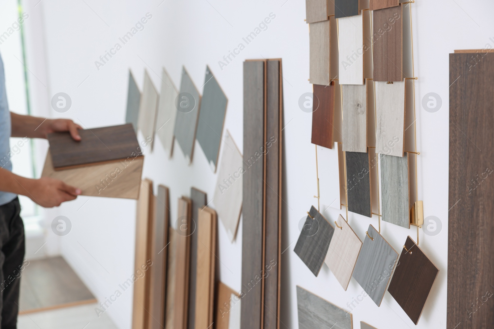 Photo of Man with different samples of wooden flooring indoors, closeup