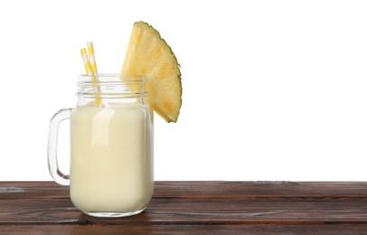 Photo of Tasty pineapple smoothie in mason jar and slice of fruit on wooden table against white background. Space for text