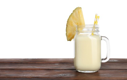 Photo of Tasty pineapple smoothie in mason jar and slice of fruit on wooden table against white background. Space for text