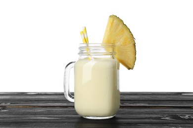 Photo of Tasty pineapple smoothie in mason jar and slice of fruit on wooden table against white background