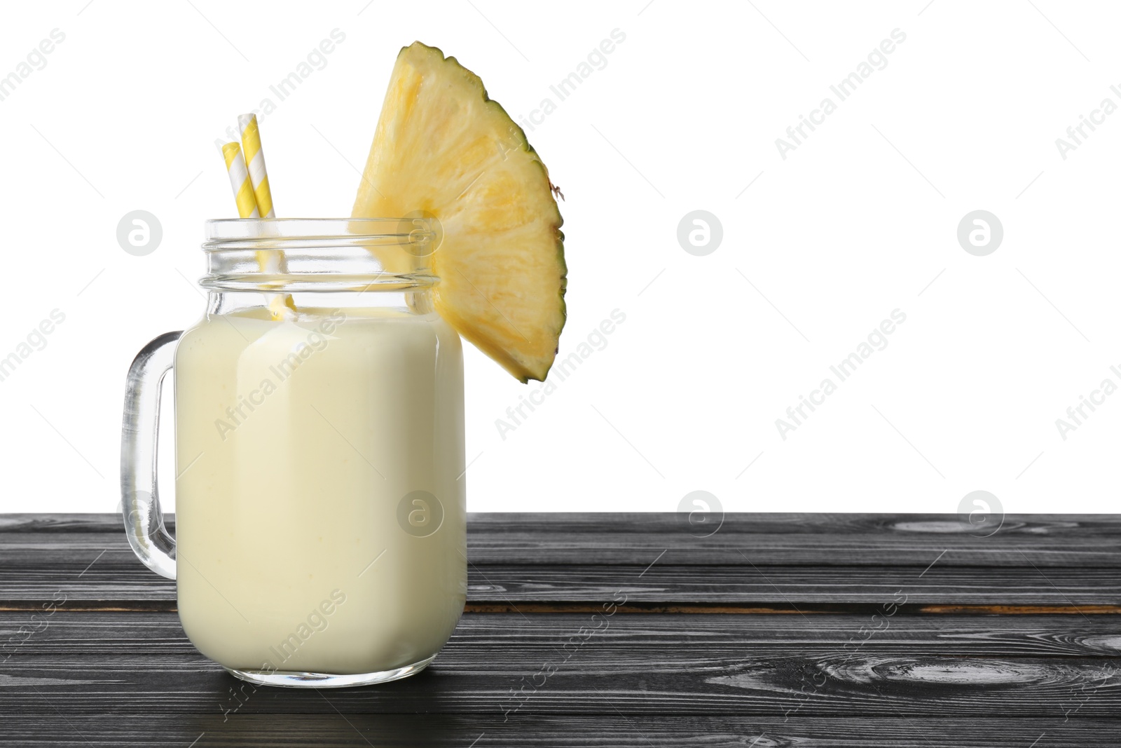 Photo of Tasty pineapple smoothie in mason jar and slice of fruit on wooden table against white background. Space for text