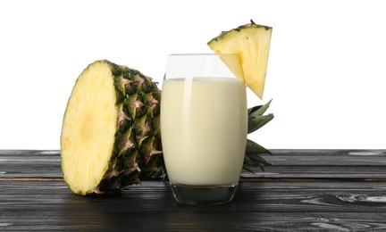 Photo of Tasty pineapple smoothie in glass and slices of fruit on wooden table against white background