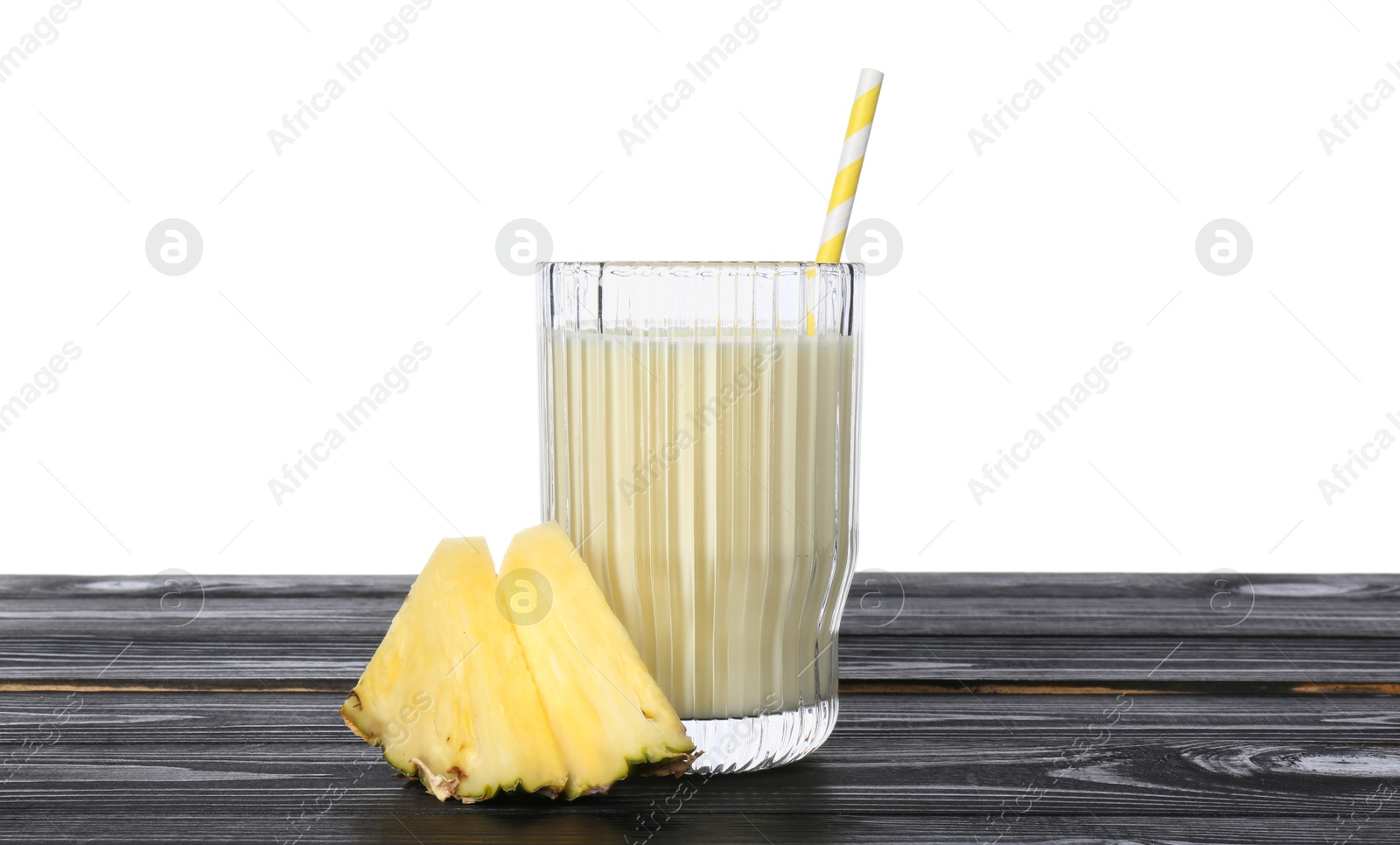 Photo of Tasty pineapple smoothie in glass and slices of fruit on wooden table against white background