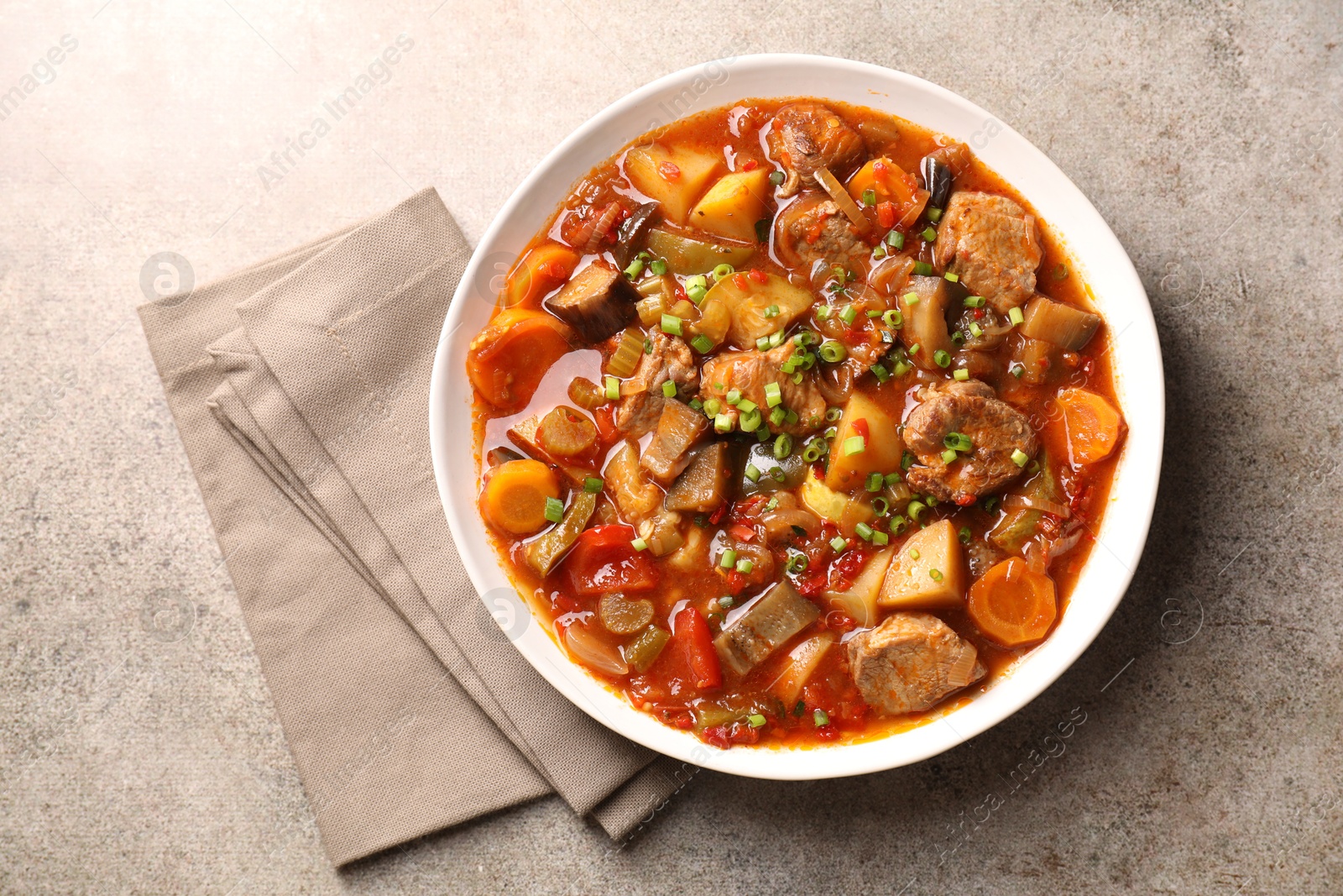 Photo of Delicious stew with vegetables in bowl on light grey table, top view