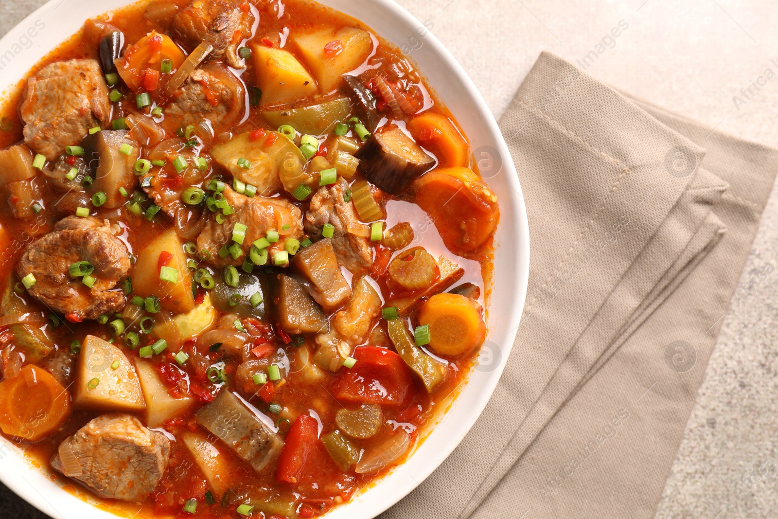 Photo of Delicious stew with vegetables in bowl on light grey table, top view