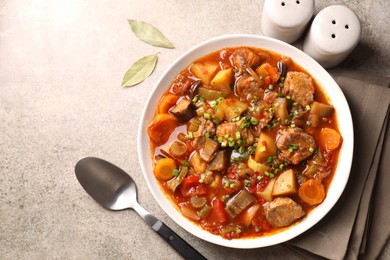 Photo of Delicious stew with vegetables in bowl, spices and spoon on light grey table, top view