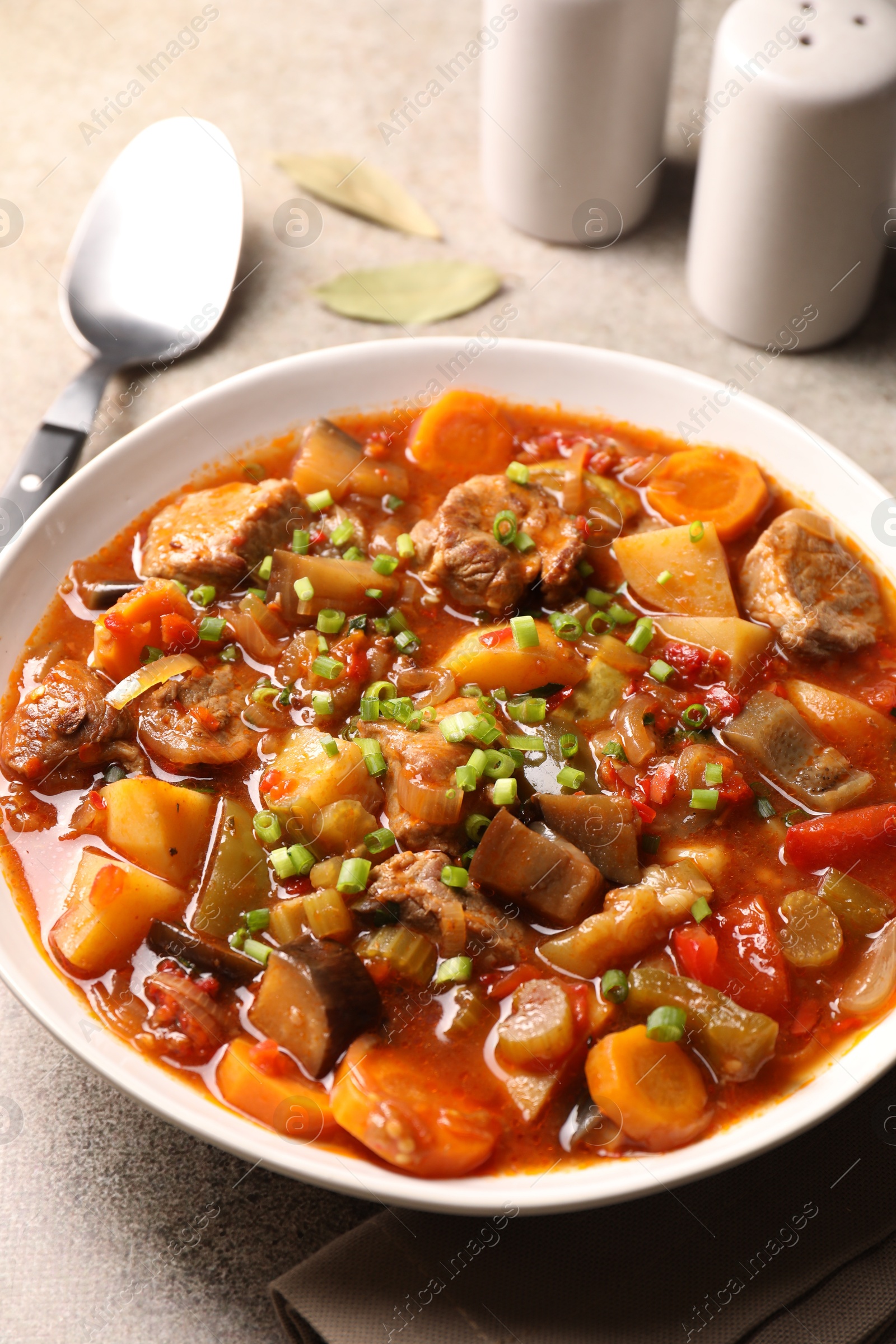 Photo of Delicious stew with vegetables in bowl on light grey table, closeup