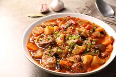 Delicious stew with vegetables in bowl on light grey table, closeup