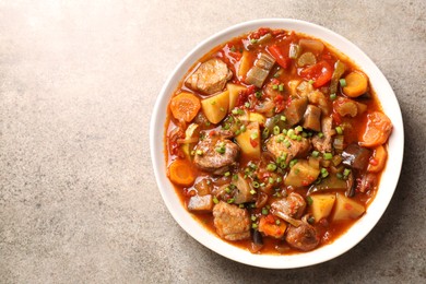 Delicious stew with vegetables in bowl on light grey table, top view. Space for text