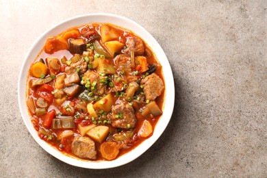 Photo of Delicious stew with vegetables in bowl on light grey table, top view. Space for text