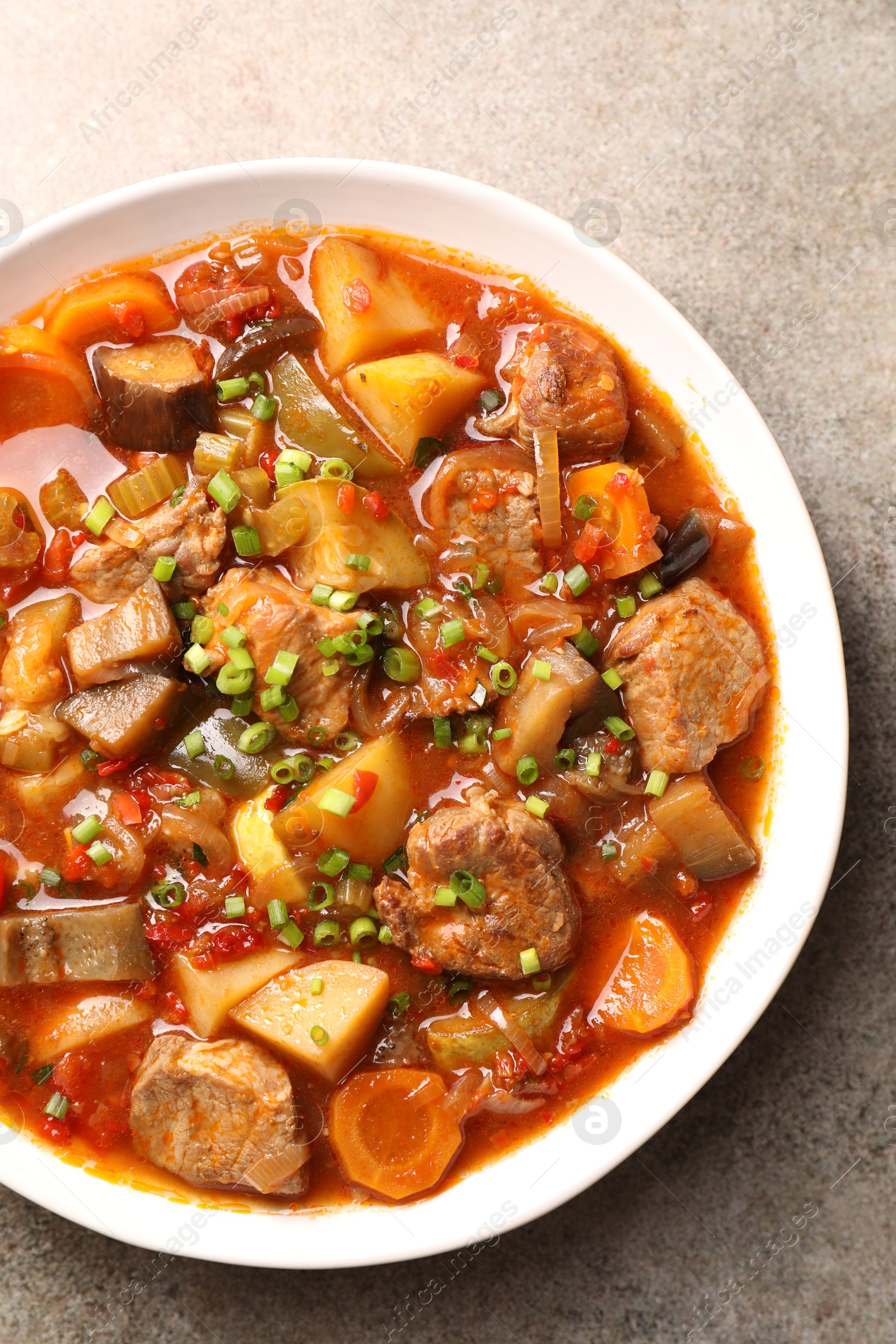 Photo of Delicious stew with vegetables in bowl on light grey table, top view