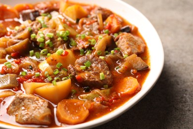 Delicious stew with vegetables in bowl on light grey table, closeup