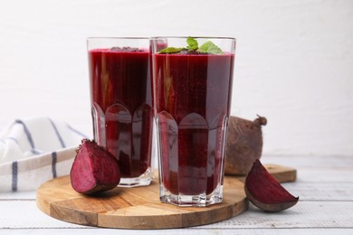 Photo of Fresh beetroot smoothie in glasses on white wooden table. Vegan drink