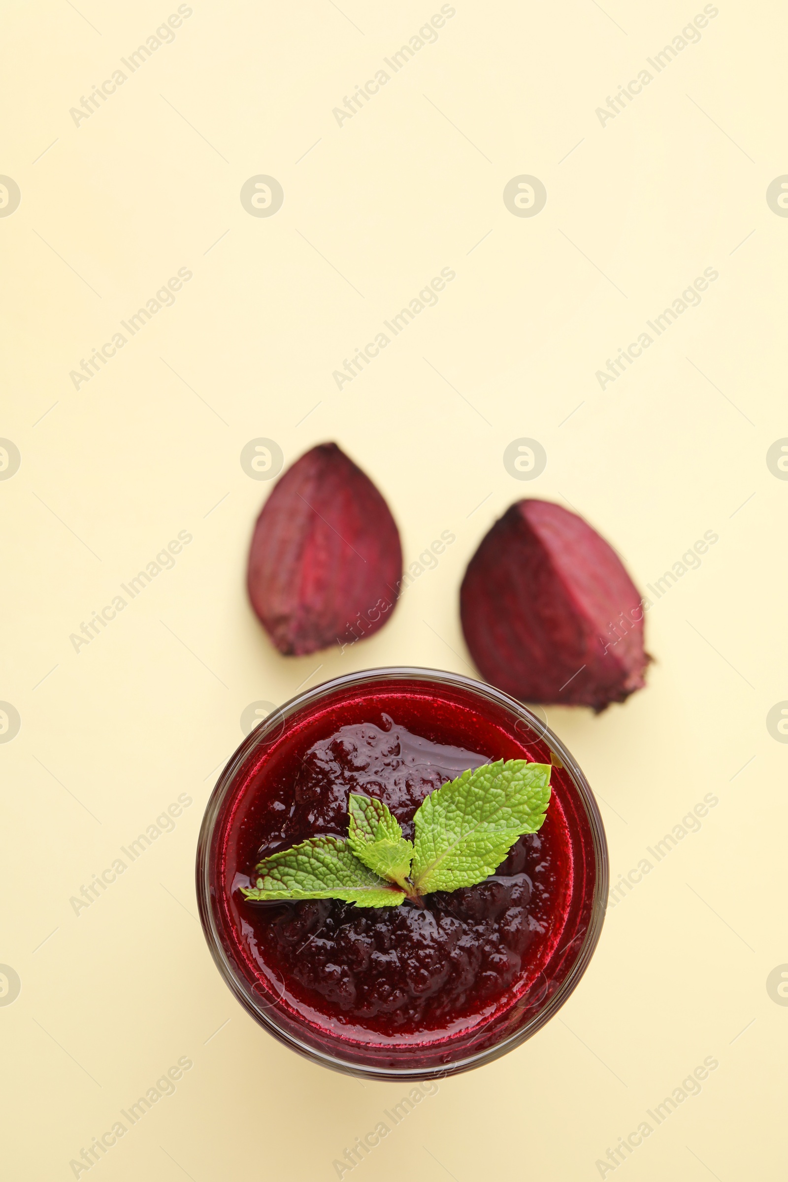 Photo of Fresh beetroot smoothie with mint in glass on beige background, top view. Space for text