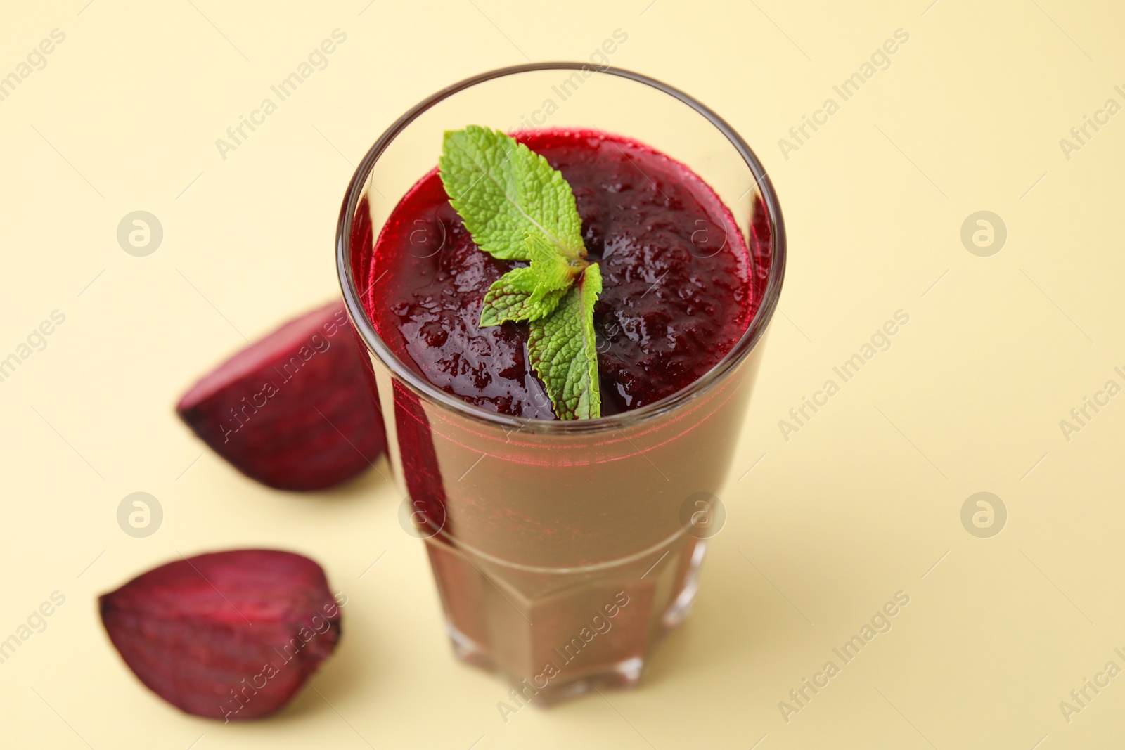 Photo of Fresh beetroot smoothie with mint in glass on beige background, closeup. Vegan drink