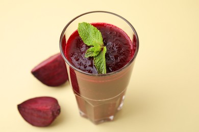 Fresh beetroot smoothie with mint in glass on beige background, closeup. Vegan drink