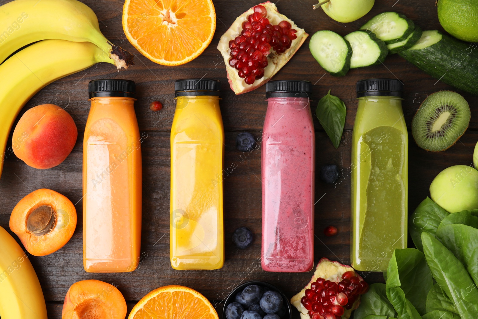 Photo of Glass bottles of tasty smoothies and different products on wooden table, flat lay