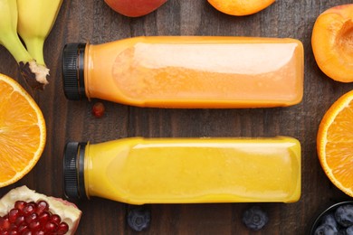 Glass bottles of tasty smoothies and different products on wooden table, flat lay