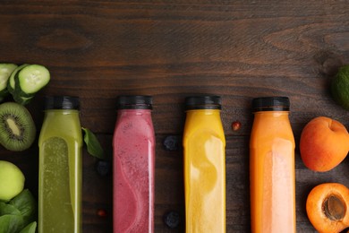 Photo of Glass bottles of tasty smoothies and different products on wooden table, flat lay. Space for text