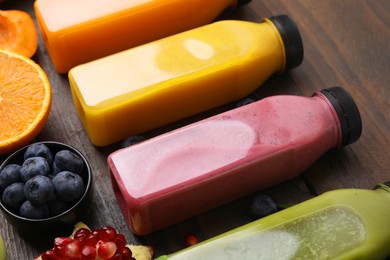 Glass bottles of tasty smoothies and different products on wooden table