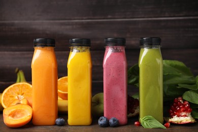 Photo of Glass bottles of tasty smoothies and different products on wooden table