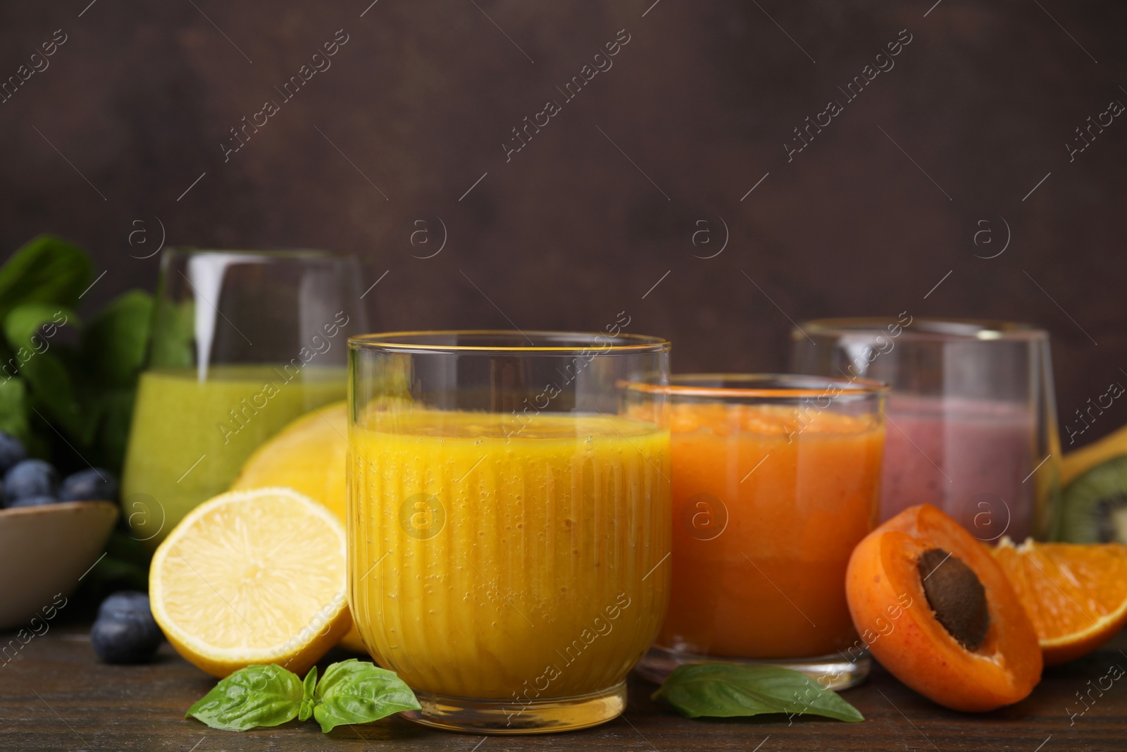 Photo of Tasty smoothies in glasses and ingredients on wooden table, closeup