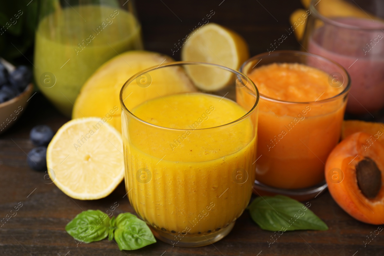 Photo of Tasty smoothies in glasses and ingredients on wooden table, closeup