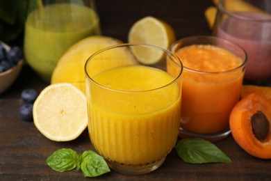 Tasty smoothies in glasses and ingredients on wooden table, closeup