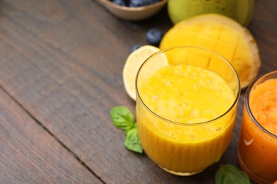 Tasty smoothies in glasses and ingredients on wooden table, closeup. Space for text