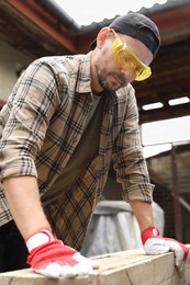 Man in goggles working with wood outdoors