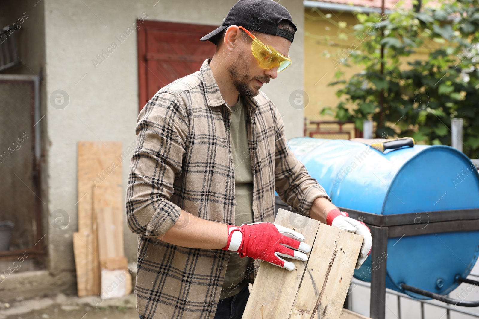 Photo of Man in goggles working with wood outdoors