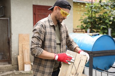 Man in goggles working with wood outdoors