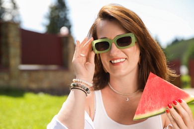 Photo of Happy woman with slice of juicy watermelon outdoors, space for text