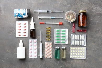 Pharmacist. Different pills, syringes, bottles of medical drops and ampoules on grey table, flat lay