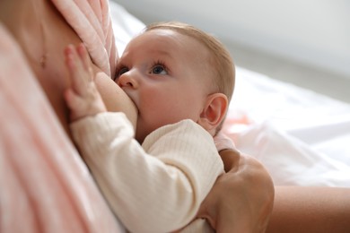 Photo of Mother breastfeeding her little baby indoors, closeup