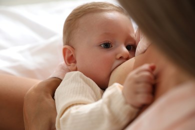 Photo of Mother breastfeeding her little baby indoors, closeup