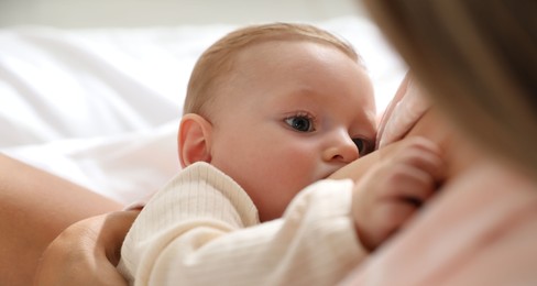 Mother breastfeeding her little baby indoors, closeup