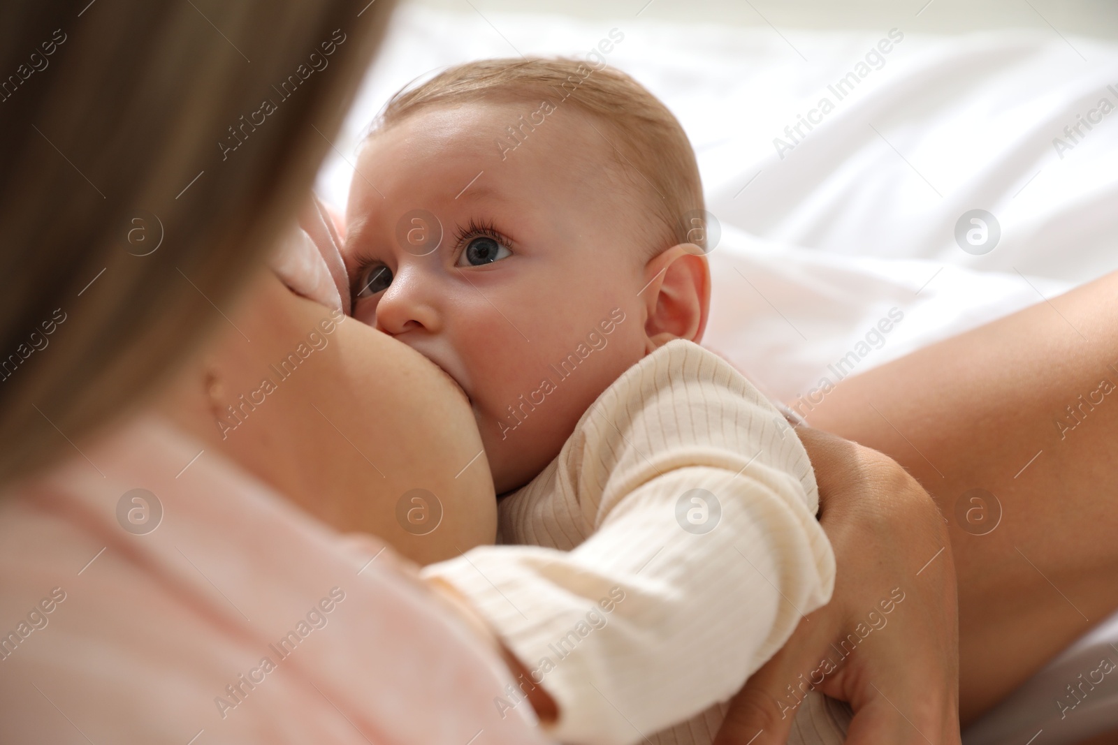 Photo of Mother breastfeeding her little baby indoors, closeup