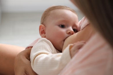 Photo of Mother breastfeeding her little baby indoors, closeup