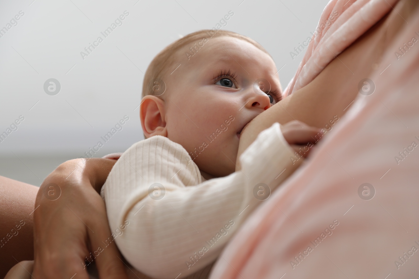 Photo of Mother breastfeeding her little baby indoors, closeup