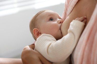 Mother breastfeeding her little baby indoors, closeup